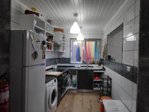 a kitchen with a refrigerator and a washer and dryer at By the Sea Azores in Ribeira Grande