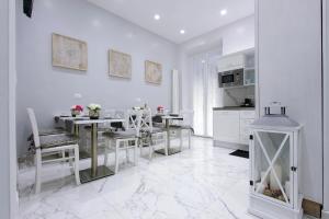 a white kitchen with white tables and chairs at Roman Holiday Colosseo in Rome