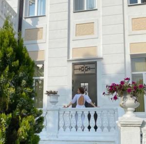 スフミにあるБутик-отель Белый Дом Балериныの建物のバルコニーに立つ女性