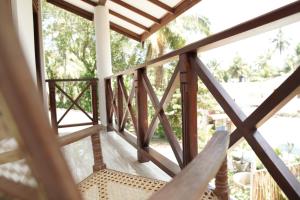 a balcony with a wooden railing and a chair at Surf Nest Hiriketiya in Dickwella