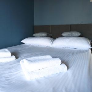 Una cama blanca con 3 almohadas y toallas. en Na Sadowej, en Grodzisk Mazowiecki