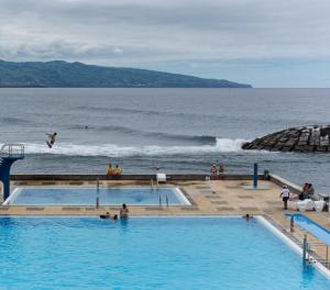a group of people in a swimming pool next to the ocean at By the Sea Azores in Ribeira Grande