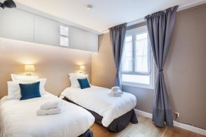 two beds in a room with a window at Suite Appart Place Versepuy in Chantilly