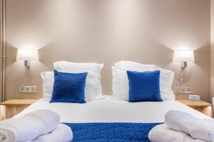 a bedroom with a large bed with blue and white pillows at Suite Appart Place Versepuy in Chantilly