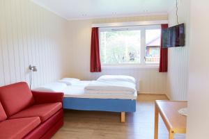 a bed in a room with a red couch and a window at Skjåk Turistheim in Skjåk