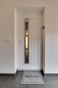 a white door with a welcome sign on it at Forest Földvár Apartmanok By BLTN in Balatonföldvár