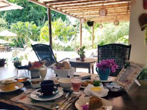 a table with food on top of it with chairs at Pousada Tubarão in Arraial d'Ajuda