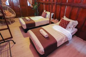 two beds in a room with wooden walls at 8 Wooden Inn LOT 1806 in Kampong Alor Gajah