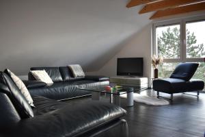 a living room with black leather furniture and a tv at Ferienwohnung 360° in Himmelkron