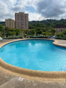 een groot blauw zwembad met gebouwen op de achtergrond bij Light Escape in Ocho Rios