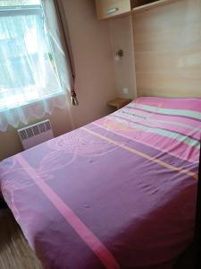 a pink bed in a room with a window at Bungalow de 3 chambres avec piscine partagee et jardin amenage a Onzain in Onzain