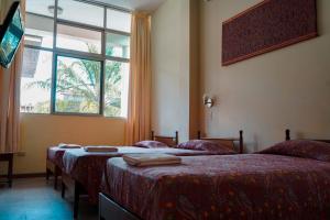 2 camas en una habitación con ventana en Grand Hotel Mercedes en Pucallpa