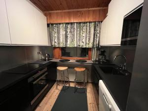 eine Küche mit schwarzen Arbeitsflächen und zwei Hockern in der Unterkunft Huoneisto Tikkakoski - Apartment in Tikkakoski in Tikkakoski