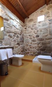 Baño con paredes de piedra, aseo y lavamanos en Casa Rural A Bouciña, en Hío