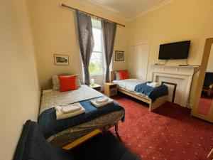 a bedroom with two beds and a fireplace and a tv at Airdenair Guest House in Edinburgh