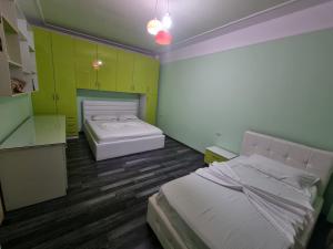 two beds in a room with green cabinets at MoonShine Apartament in Tirana