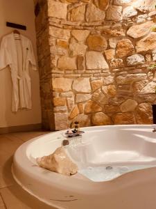 La salle de bains est pourvue d'une baignoire et d'un mur en pierre. dans l'établissement Hotel Villa Murano, à San Cristóbal de Las Casas
