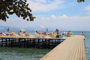 a group of people sitting on a pier on the water at Dassia Beach Hotel in Dassia