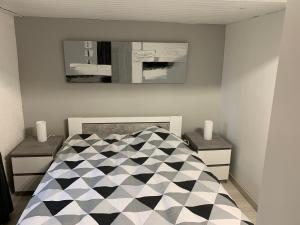 a bedroom with a black and white bed and a mirror at maison chaleureuse en plein coeur de Livarot in Livarot