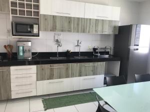 a kitchen with wooden cabinets and a sink and a refrigerator at Casa Mares do Sul in Marechal Deodoro