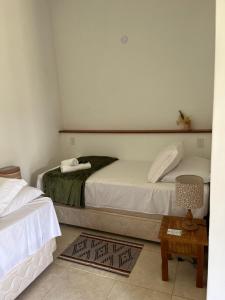 a small bedroom with a bed and a table at POUSADA PÔR DO SOL in Ipiabas