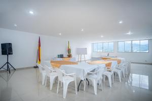 Ayenda Gold Plaza في إباغويه: غرفة طعام مع طاولات بيضاء وكراسي بيضاء
