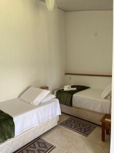 2 camas en una habitación con paredes blancas en POUSADA PÔR DO SOL, en Ipiabas