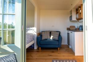 a room with a blue chair and a bed at Scalderskew Shepherds Hut in Gosforth