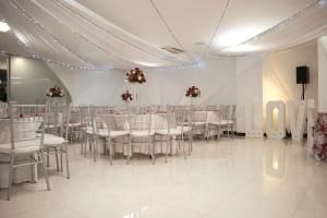 Un salón de banquetes con mesas y sillas blancas. en Hotel Marrakech Cali, en Cali