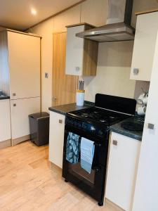 a kitchen with a black stove and white cabinets at Hoburne Devon Bay Paignton L48 in Paignton