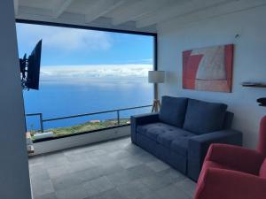 a living room with a couch and a large window at Bungalowmirador in Fuencaliente de la Palma