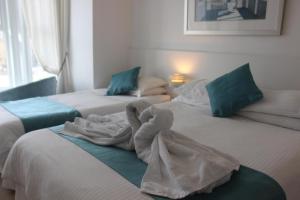 two beds with towels on them in a room at Silver Birch in Looe