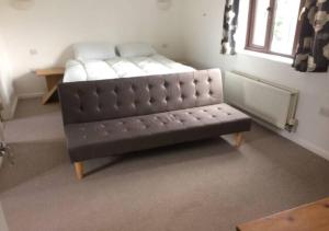 a leather couch in a room with a window at 6 Bedroom House For Corporate Stays in Kettering in Kettering