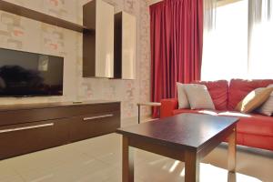 salon z czerwoną kanapą i telewizorem w obiekcie 101 Moroni by Cast Renting w Gżirze
