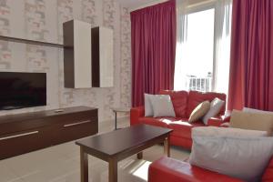 a living room with a red couch and a tv at 101 Moroni by Cast Renting in Il-Gżira