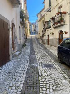 una calle adoquinada con un coche aparcado en el lateral en La casetta della nonna en Caramanico Terme