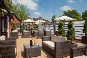 un patio con sedie, tavoli e ombrelloni in vimini di The Winchester Hotel and Spa a Winchester