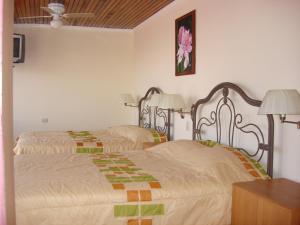 Hotel La Guaria Inn & Suites في ألاخويلا: سريرين في غرفة بجدران بيضاء