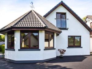 a white house with windows and a roof at Little Chestnut in Muir of Ord