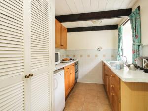 eine Küche mit Holzschränken und weißen Geräten in der Unterkunft Coachman's in Forrabury