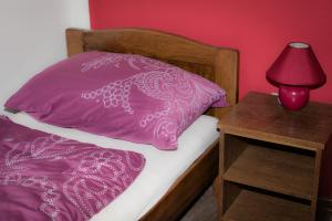 - un lit avec un oreiller rose et une lampe rouge sur une table de nuit dans l'établissement Guesthouse Pink Panther, à Udbina