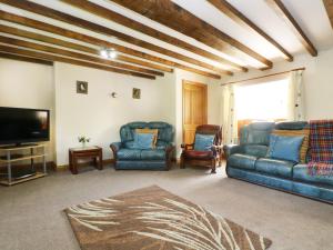 a living room with a couch and chairs and a tv at Eastcott Farmhouse in Holsworthy