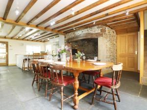 a dining room with a table and a stone fireplace at Eastcott Farmhouse in Holsworthy