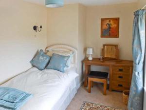 a bedroom with a bed with blue pillows and a desk at Tuckermarsh Quay River Cottage 2 in Bere Alston