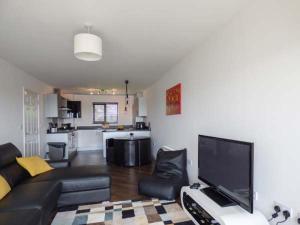 a living room with a black couch and a kitchen at Tehidy in Charlestown