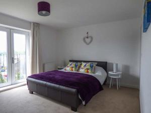 a bedroom with a bed with purple sheets and a window at Tehidy in Charlestown