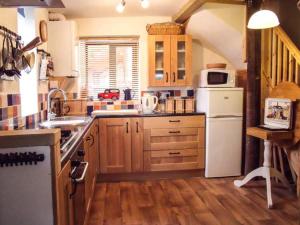 a kitchen with wooden cabinets and a white refrigerator at Groom Cottage in Bude