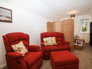 un soggiorno con 2 sedie rosse e una sedia di Bramble Barn a Bodmin