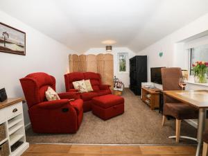 uma sala de estar com uma cadeira vermelha e uma mesa em Bramble Barn em Bodmin