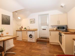 una cucina con mobili bianchi, lavatrice e asciugatrice di Bramble Barn a Bodmin